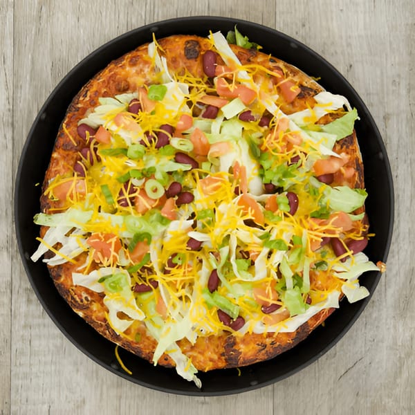 Pijja Paradise taco pizza with shredded lettuce, cheese, tomatoes, kidney beans, and green onions.