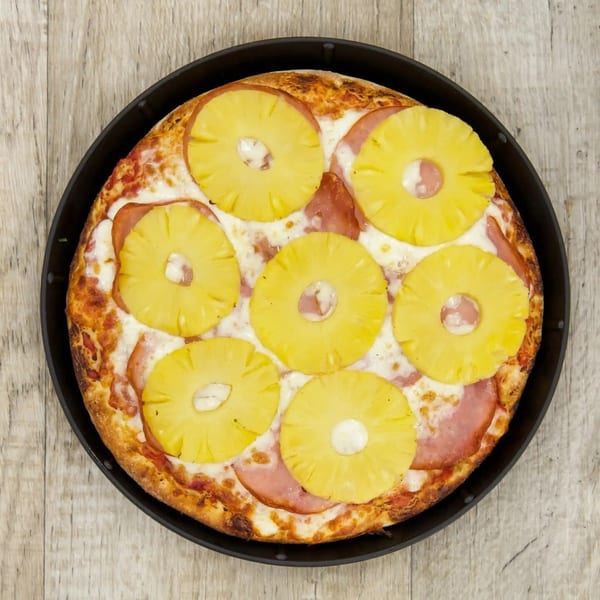 Pijja Paradise's Hawaiian pizza, topped with pineapple rings and ham, in a dark pan.